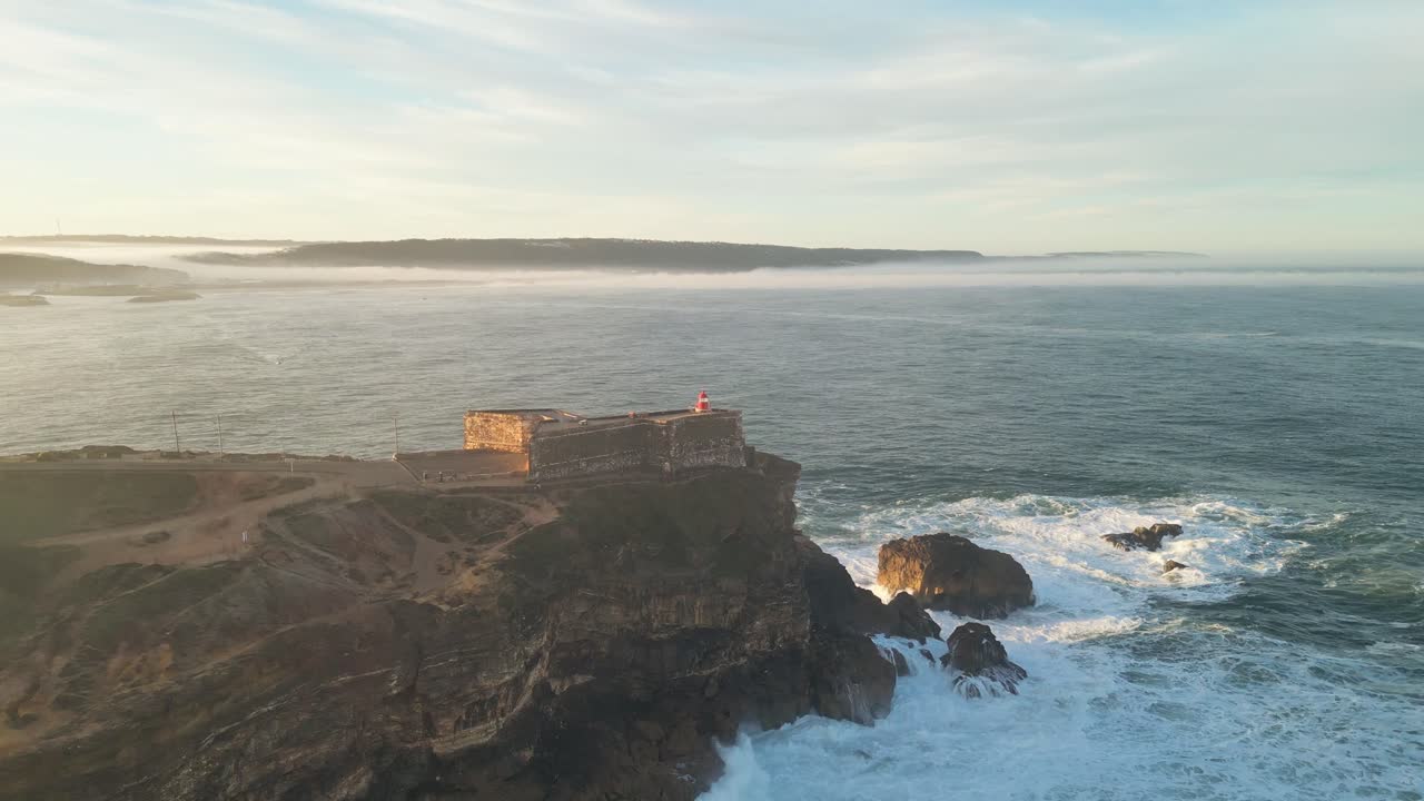 Scenic coastal view of the Farol lighthouse in Nazaré, Portugal, with waves crashing