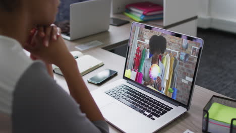 mid section of african american woman having a video call with female colleague on laptop at office