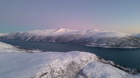 aerial view of norwegian fjords at sunset with snowy mountains and blue sea in ersfjordvegen