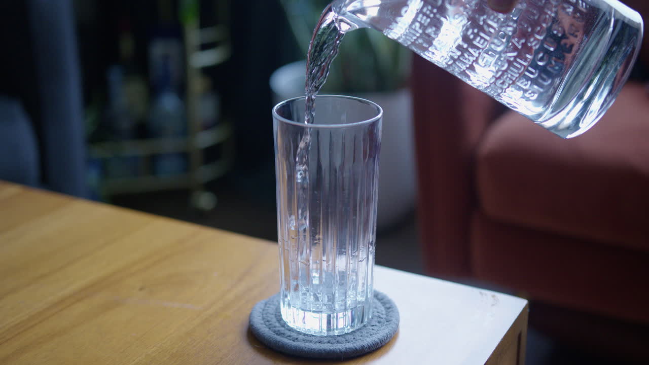 Slow Motion Wide Shot of Water Being Poured Into a Glass Cup