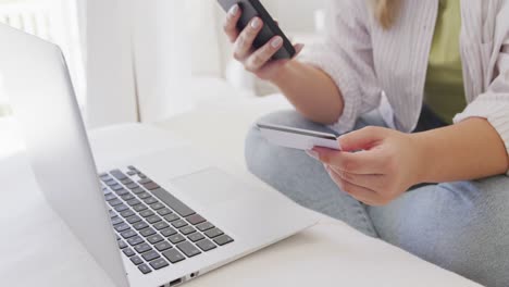 mujer caucásica de talla grande usando un teléfono inteligente y sosteniendo una tarjeta de crédito en cámara lenta
