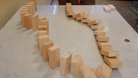 Wooden-domino-pieces-falling-in-ripple-effect-on-a-table