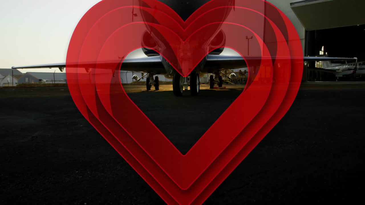 Red heart animation over airplane parked on tarmac at airport