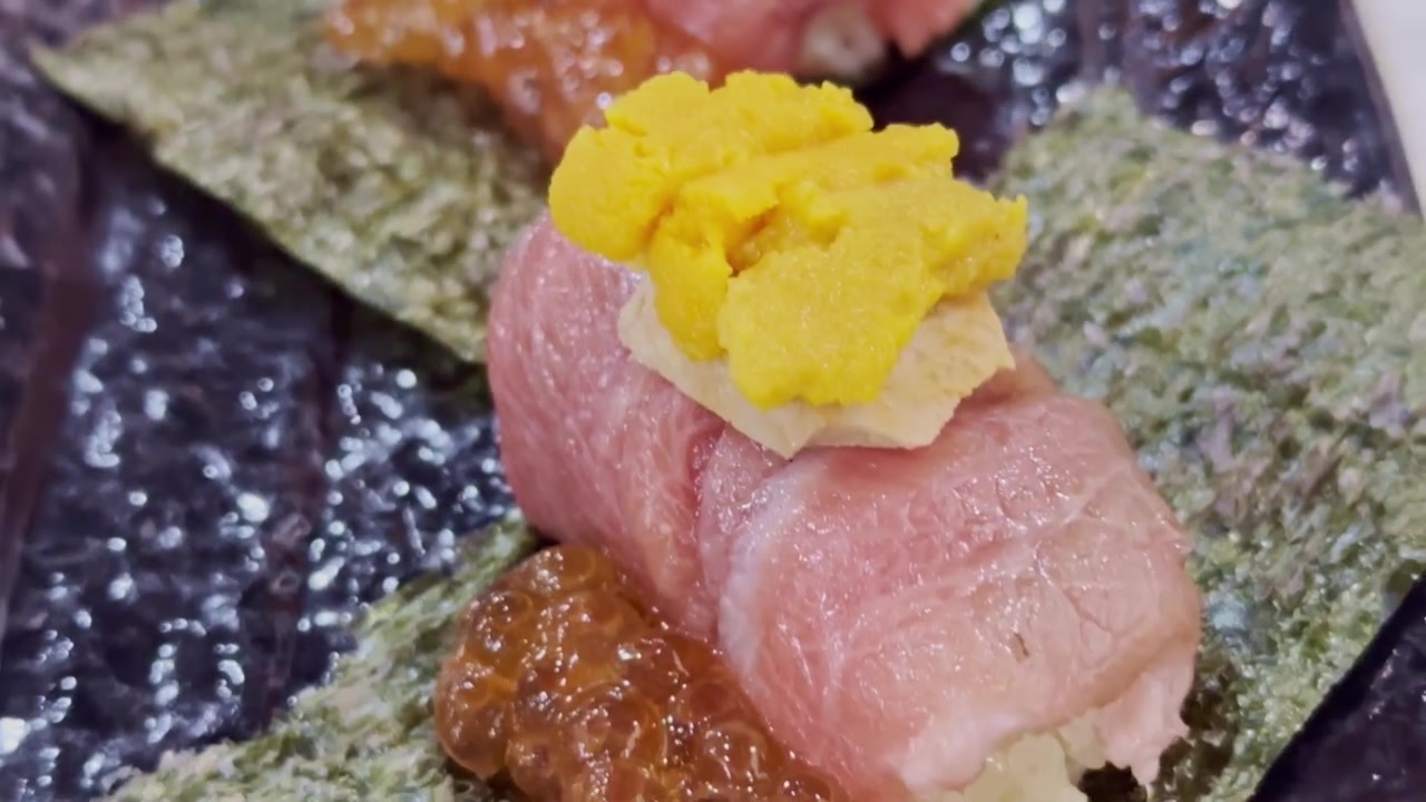 Primo piano di un hand roll di otoro avvolto in alga nori e guarnito con foie gras pregiato e uni fresco, che mostra un'elegante esperienza culinaria giapponese di lusso.