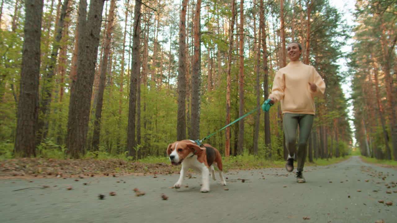 mujer corriendo con su beagle en un bosque