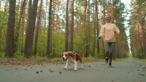 woman running with her beagle in a forest