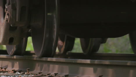 closeup on freight train wheels on train tracks passing by camera from low angle in slow motion