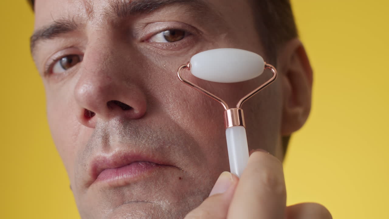 Male Millennial Massaging Face with Jade Roller