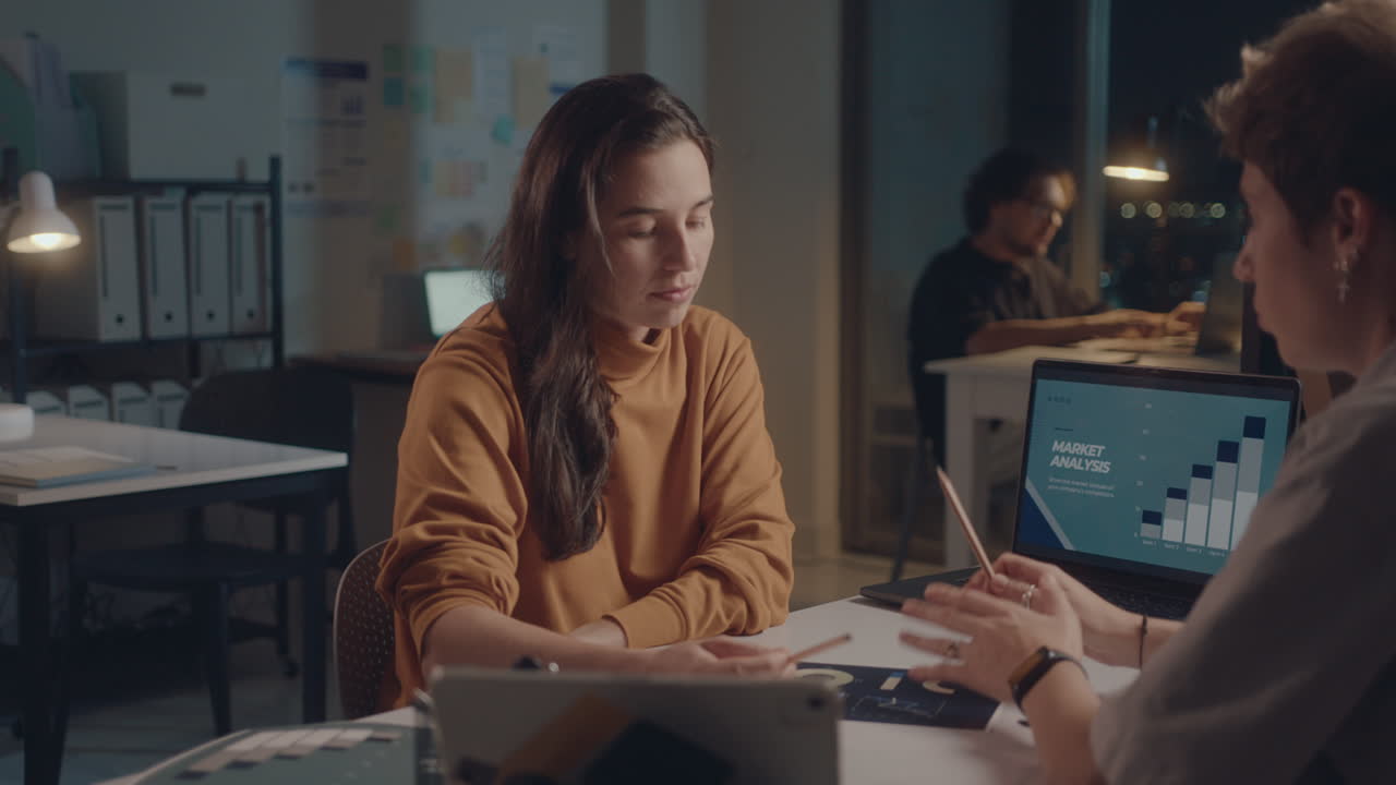 Female Colleagues Discussing Business in Office at Night