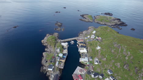 aerial dolly forward view of a small fishing village around a small sheltered harbor on a rocky peninsula in northern norway, above the arctic circle