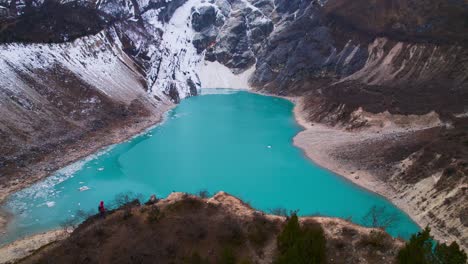 A-boy-in-a-red-jacket-standing-at-the-edge-of-a-hill-overlooking-Birendra-Lake-in-Manaslu-Circuit-Trek,-Nepal