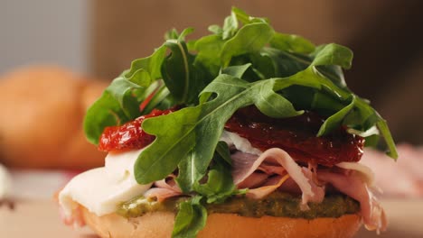 mortadella ham sandwich, traditional italian focaccia filled with thin pesto slices of mortadella, served by chef man in cafe restaurant. macro of traditional italian spanish tapas antipasti.