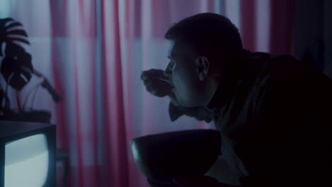 man watching tv and eating