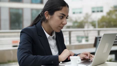 focused businesswoman using laptop in cafe