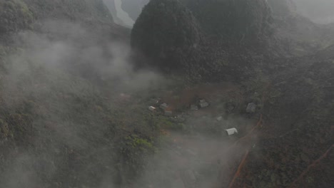 Flying-backwards-at-small-local-village-at-Ma-pi-leng-pass-at-Vietnam,-aerial