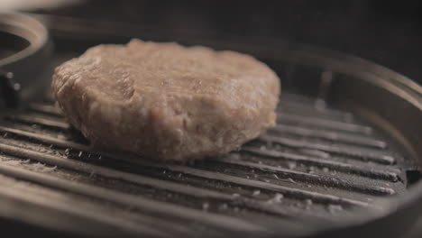 raw beef or chicken burger on grill being prepared for a delicious burger sandiwich , with a black background and simple light set up shot on raw 4k