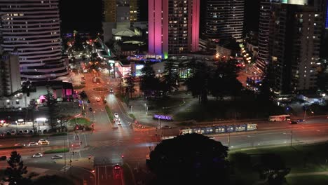 aerial view of a vibrant city at night with illuminated skyscrapers, busy roads, and moving trams