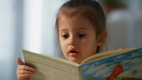 young girl reading a book with focused expression