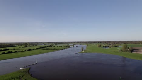 Intersection-of-river-IJssel-with-Twentekanaal-canal-with-large-area-for-manoeuvre-and-navigating-in-Dutch-valley-Netherlands-landscape-revealing-a-cargo-ship-approaching-on-inland-shipping-waterway