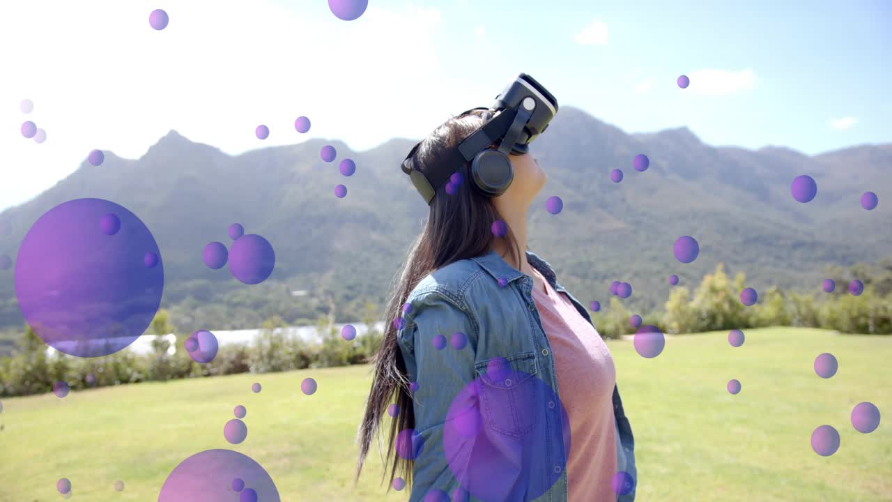 Teen wearing VR headset seeing purple orbs appearing, turning lowering arms in field testing AR