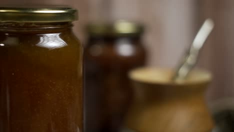 Close-up-of-rotating-mason-jar-of-peach-jam-with-"mate"-behind