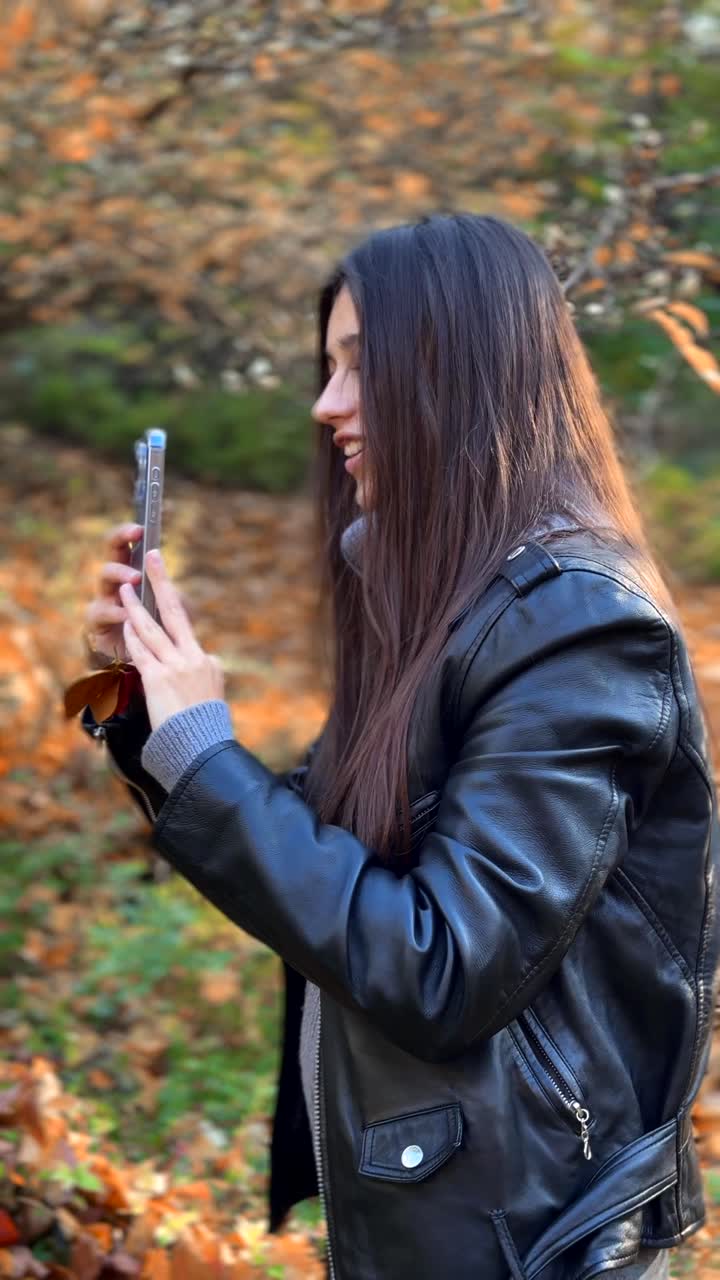 Teenage girl taking pictures in the park during fall
