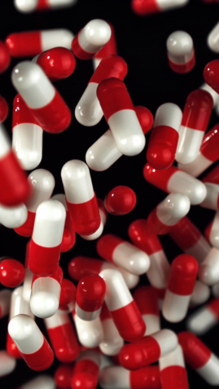 Red and White Pills Falling in Slow Motion on Black Background