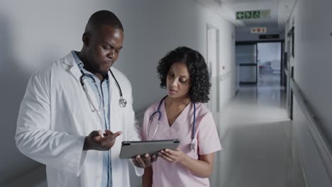 Portrait-of-happy-diverse-doctors-using-tablet-in-hospital-in-slow-motion