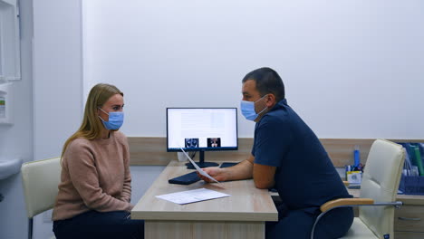 male doctor holds a sheet of paper with test results. obstetrician analyses the health check up of a blonde woman.
