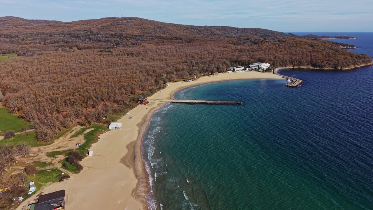 Coastal view of sandy beach along clear blue water in autumn