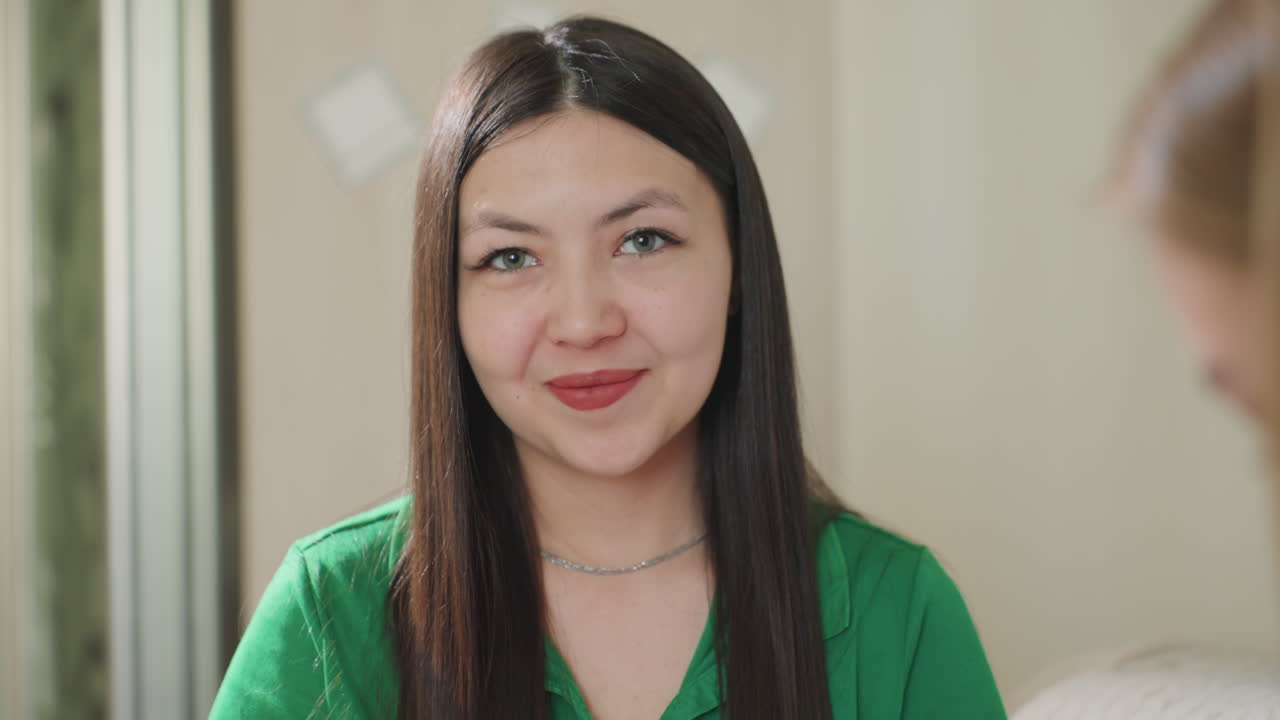 Donna sorridente che si gode la felicità in casa, scena ambientata in interni con donna asiatica felice e sorridente, donna asiatica che irradia felicità e calore in un ambiente interno confortevole e accogliente