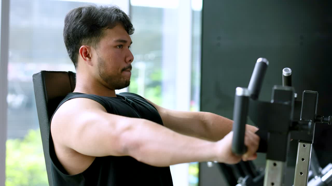 A man performs arm exercises on a gym machine in a well-lit, modern gym setting