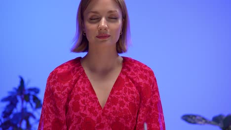 Close-up of a focused woman in a red floral blouse typing on a yellow retro typewriter against a vivid blue backdrop. The vibrant colors and vintage setting create a creative, nostalgic workspace feel