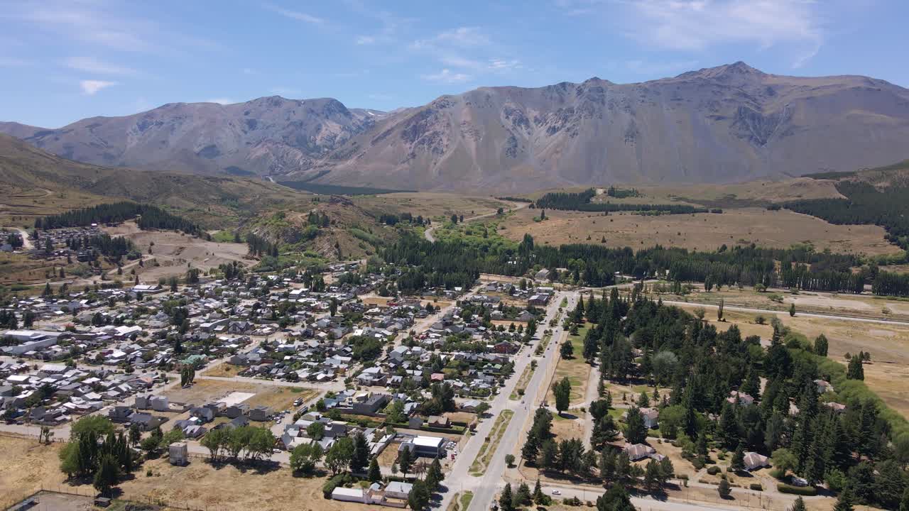 pan a la izquierda volando sobre el pueblo de esquel rodeado de árboles y montañas andinas, patagonia argentina