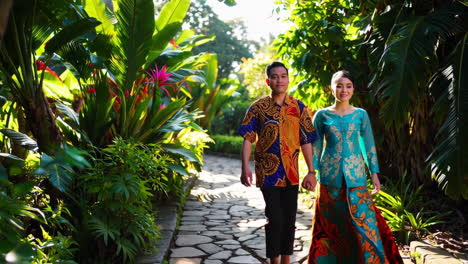 couple in traditional clothing walking through a tropical garden
