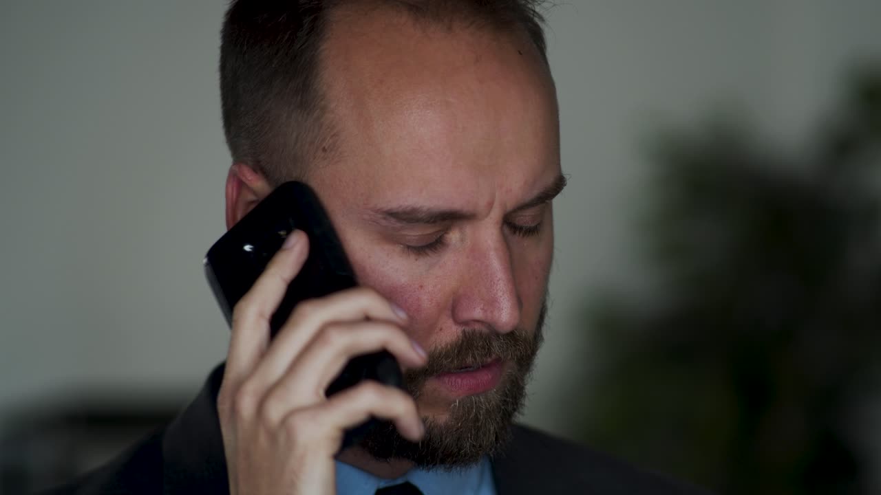 Irritated businessman talks on cellphone and shakes his head