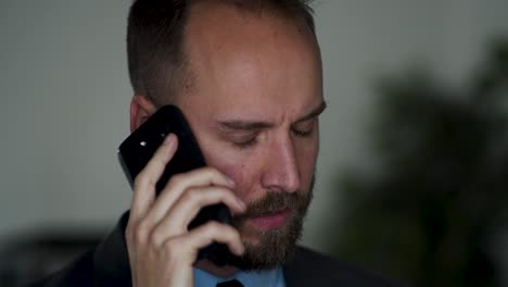 irritated businessman talks on cellphone and shakes his head