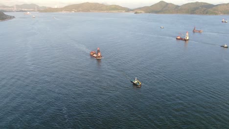 tugboat pulling a small barge in hong kong bay, aerial view