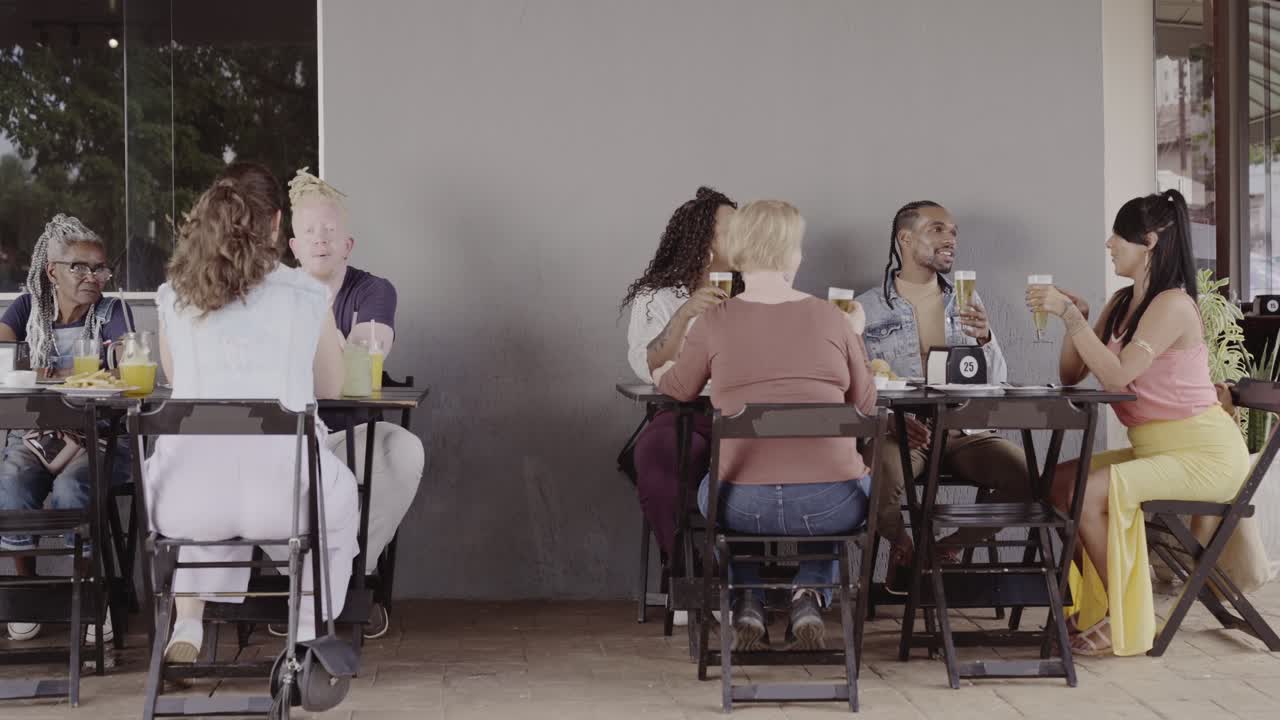 Diverse group of people enjoying drinks at an outdoor cafe patio