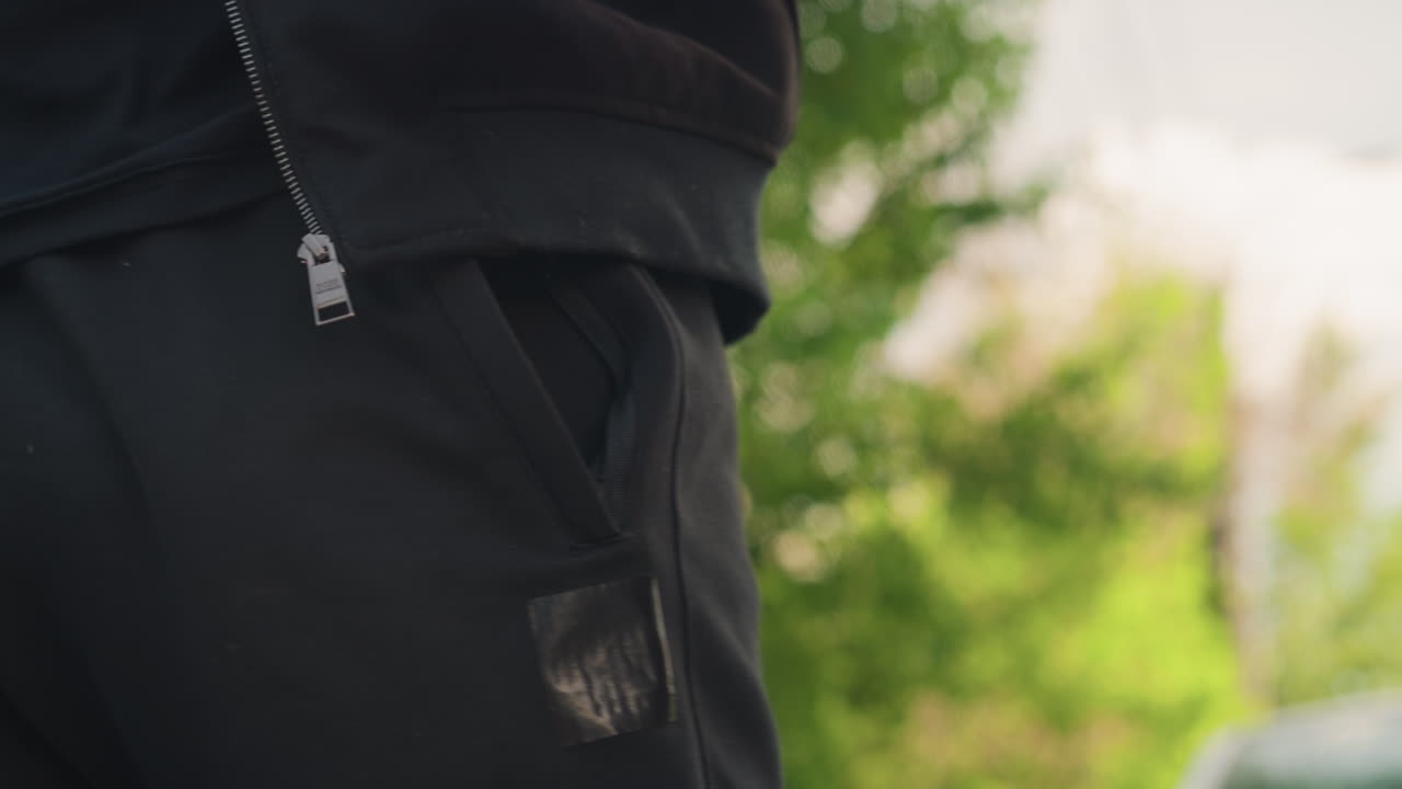 주차된 차량 옆에 열쇠를 든 남자가 서 있는 모습, 잎이 무성한 길가 배경에서 차 근처에 열쇠를 든 사람, 울창한 나무와 부드러운 하늘 배경 속에서 정차된 차량 옆에서 열쇠를 쥐고 있는 사람