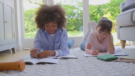 Boy-And-Girl-Lying-On-Rug-In-Lounge-At-Home-Doing-School-Homework-Together