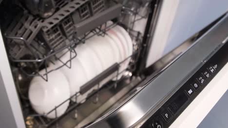 turning on the automatic dishwasher loaded with dirty dishes