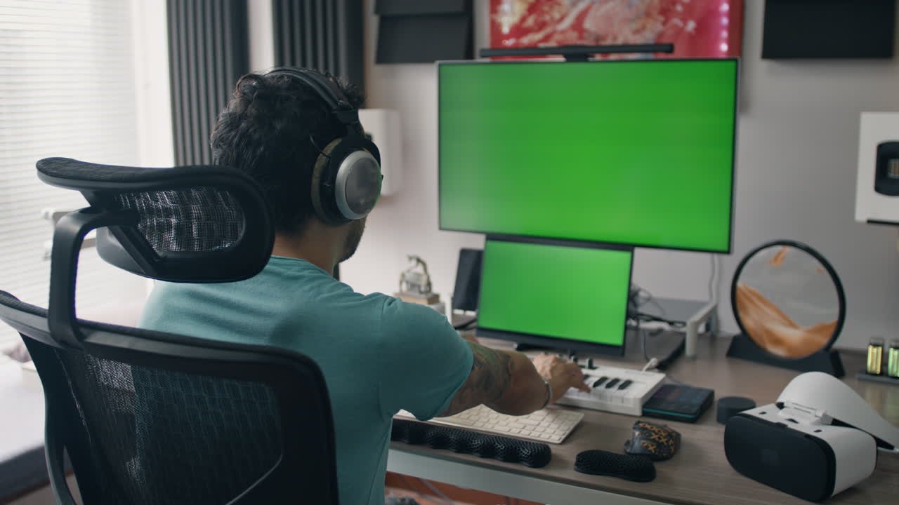 Man working in a home studio with green screen