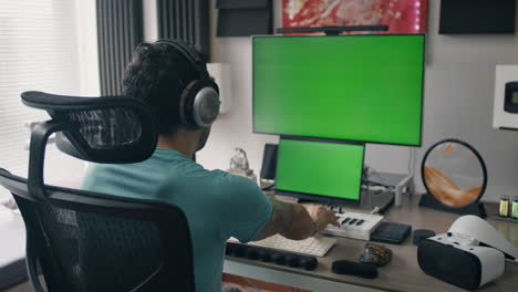 man working in a home studio with green screen