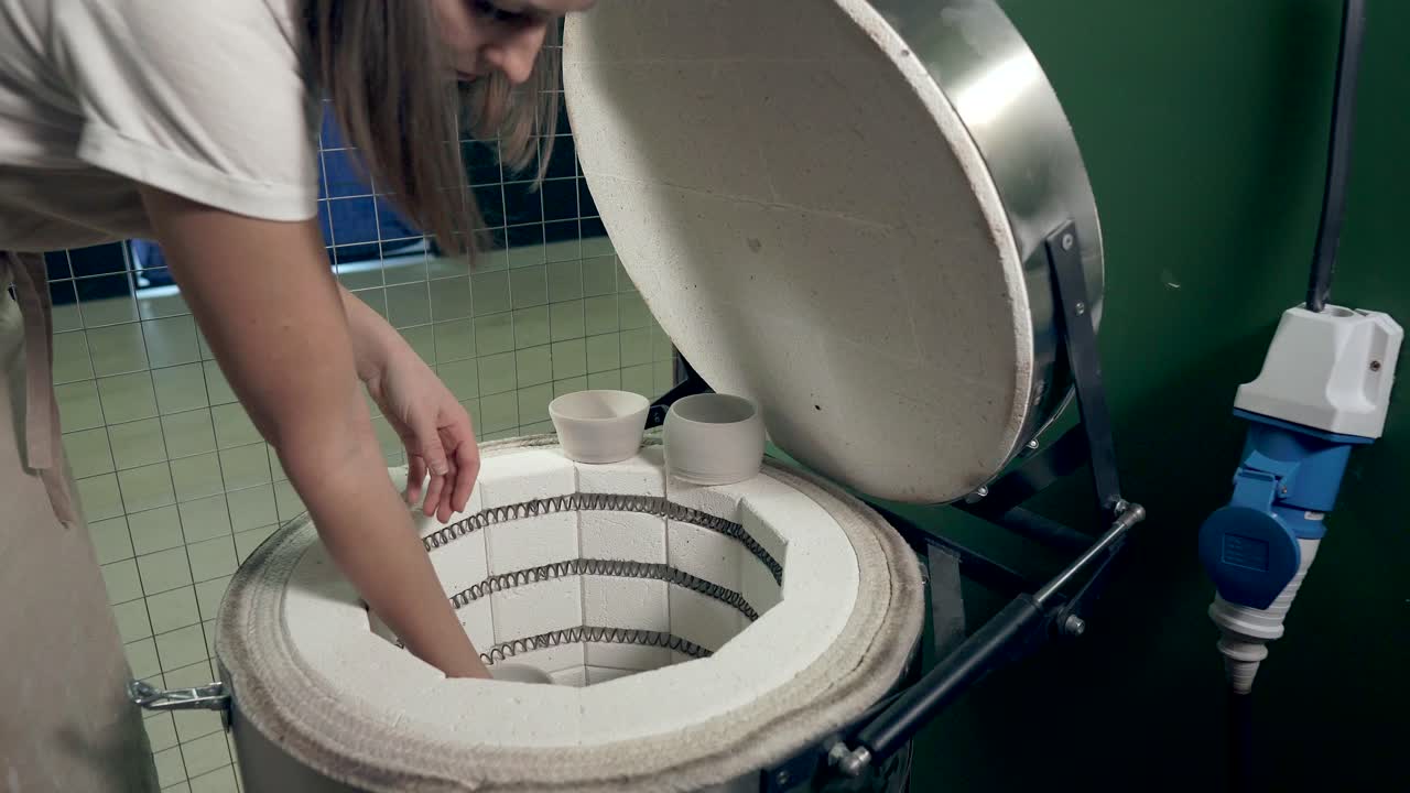 도자기 스튜디오 에서 오븐 을 사용 하는 여자