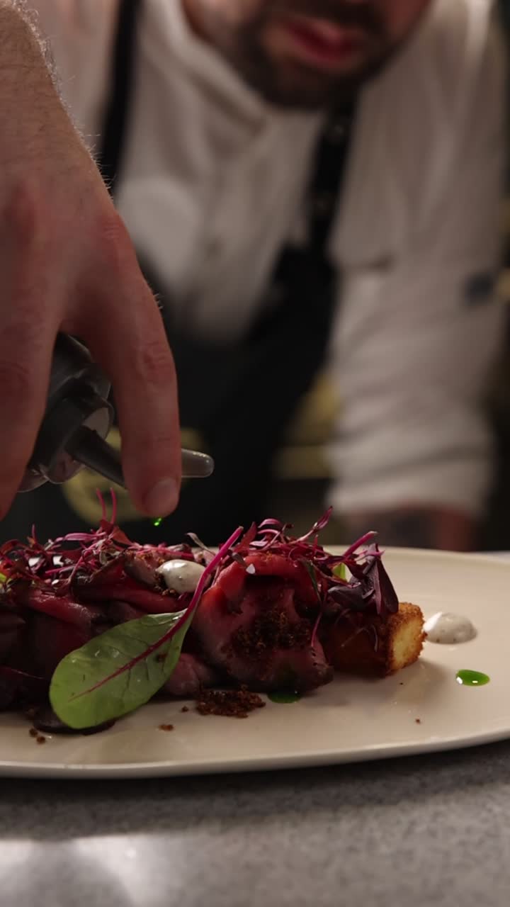 Kokki koristelee gourmet-liharuokaa kastikkeella ravintolan keittiössä