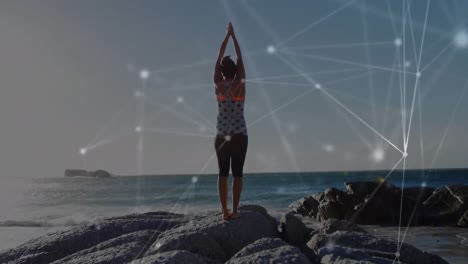 animación de una red global brillante sobre una mujer de pie junto al mar levantando los brazos