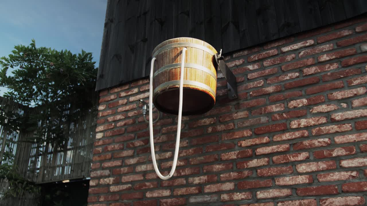 Traditional wooden sauna bucket against a textured brick wall, emphasizing relaxation and traditional spa elements