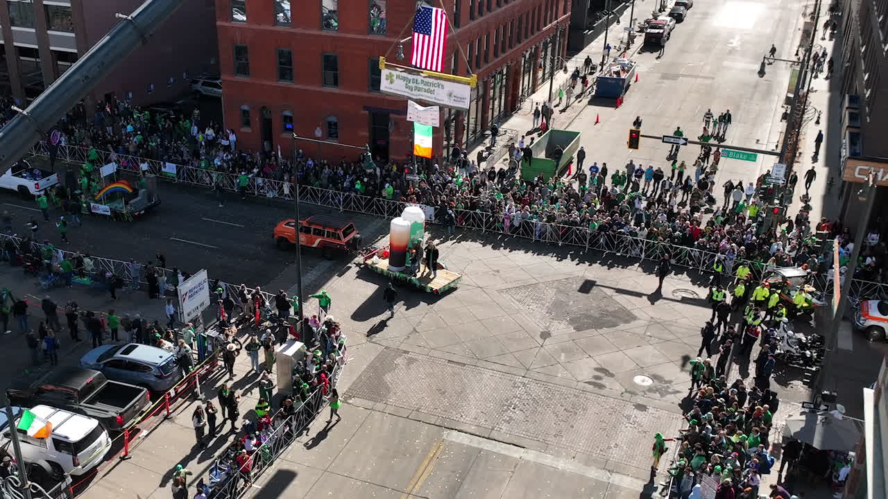 vista aérea ascendente de un carro flotante conduciendo a través de un desfile del día de san patricio en el centro de denver, colorado