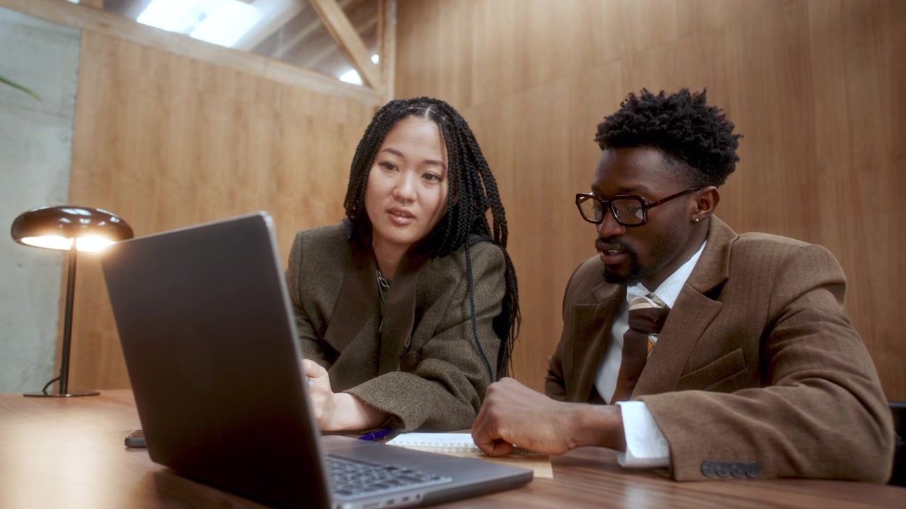 Afrikansk-amerikansk forretningsmand forklarer projekt på bærbar computer til asiatisk kollega